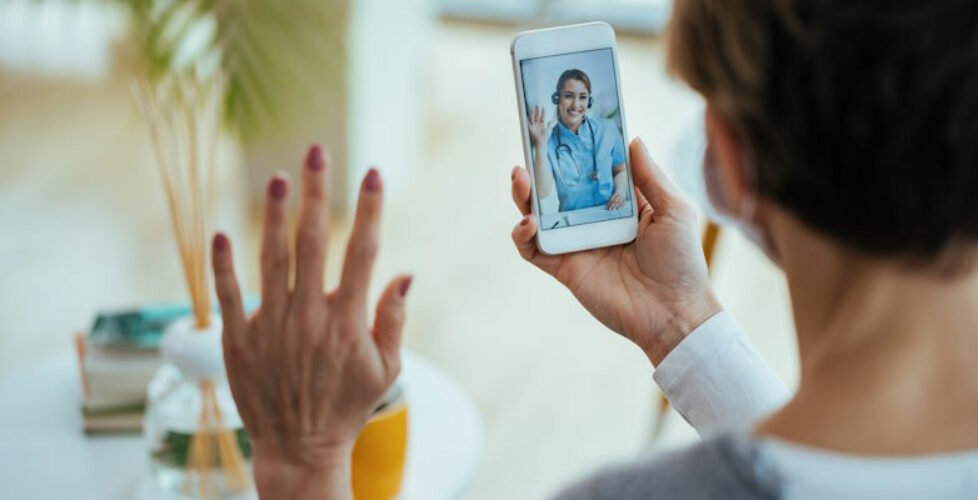 Happy doctor waving while having video call with patient over mo