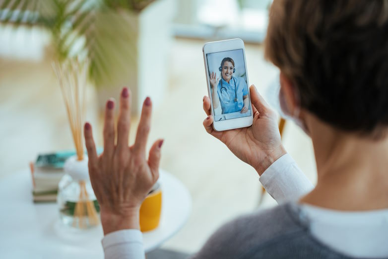Happy doctor waving while having video call with patient over mo